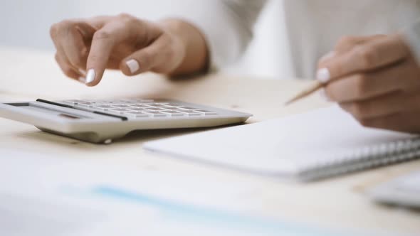 Woman using a calculator and writing notes