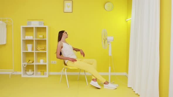 Beautiful Model Is Posing On Chair In Front of Electric Fan alt