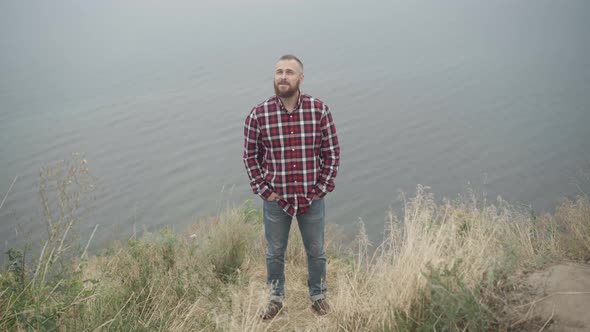 Portrait of Handsome Happy Young Man Standing on River Bank Smiling alt