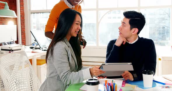 Business executives having discussion over digital tablet alt