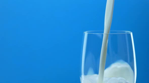 Pouring Milk in Glass on Blue Background alt