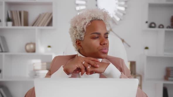 Puzzled African American Woman Sits with Tense Face in Thought alt