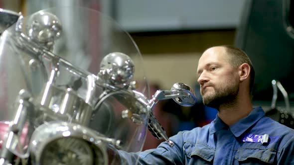 guy mechanic in blue overalls next to a motorcycle