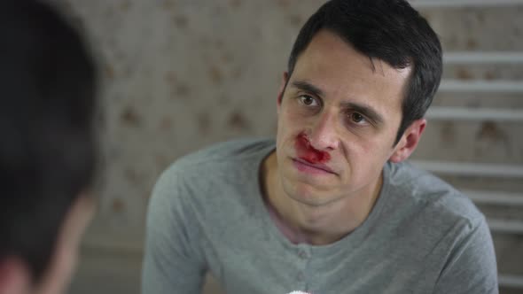 Man Wipes Nosebleed in a Front of the Mirror alt