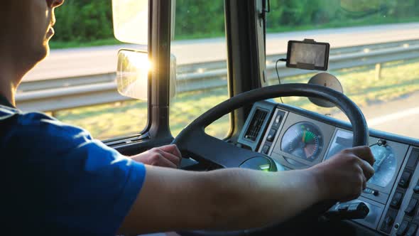 Unrecognizable Man Sitting Behind Wheel of His Truck and Driving Through Countryside. Driver Holding