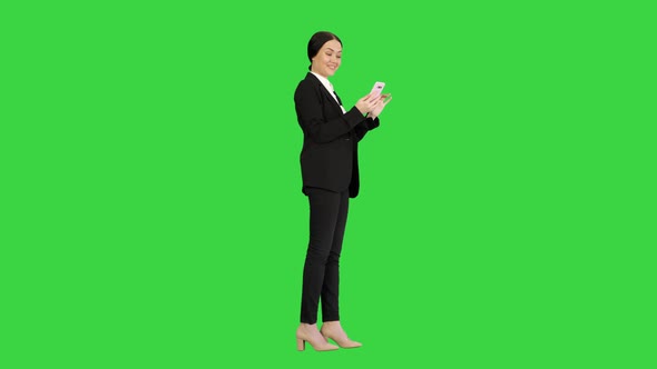 Smiling Businesswoman Checking Photos on Her Phone on a Green Screen, Chroma Key alt