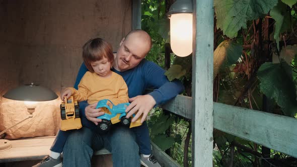 Father is Playing on Porch of the House with His Cute Little Child in a Toy Car