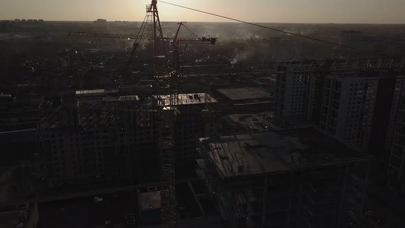 Construction Site at Sunset. Silhouette of a Construction Crane Near the Building