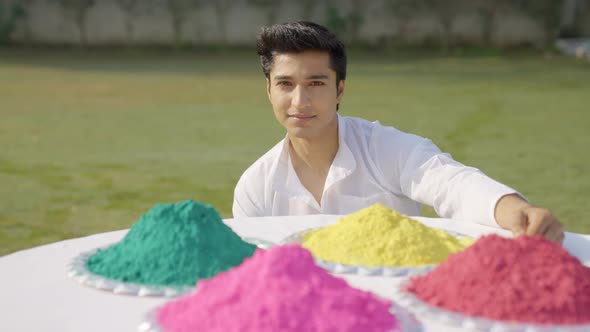 Happy Indian man looking at the Holi colors alt