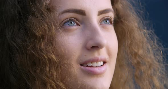 Close-up of Female Smiling Face Looks Into Distance Then Turns Blue Eyes To Camera. Portrait of alt