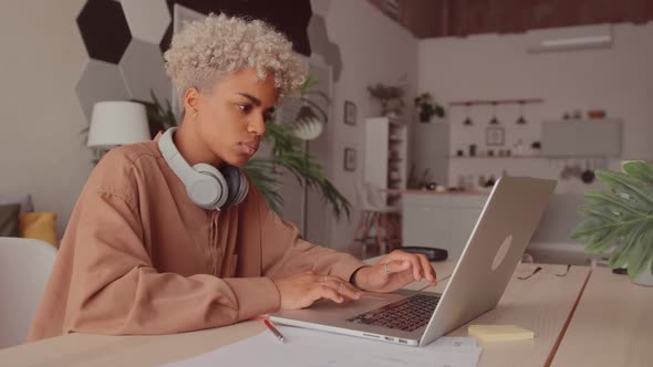 African Woman Wearing Wireless Headphones Watching Webinar with Online Teacher alt