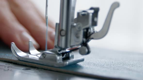 A seamstress works on a sewing machine. Close-up of a needle and thread. Clothes designer. Tailor. alt