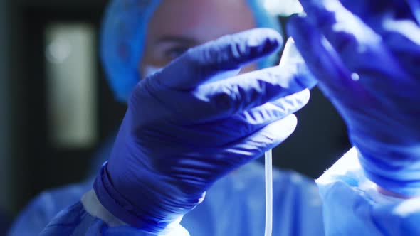 Caucasian female doctor wearing face mask preparing patient's iv drip in operating theatre alt