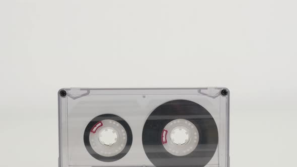 Tilting on transparent compact  audio cassette on white 4K 2160p 30fps UltraHD footage - Retro  anal alt