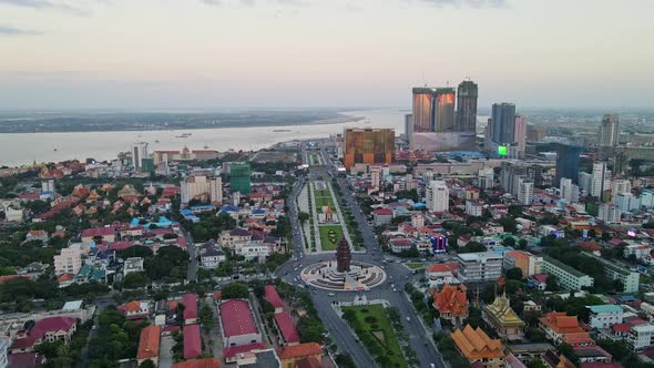 Aerial flyover Phnom Penh with Independence Monument and Mekong River during dusk. alt