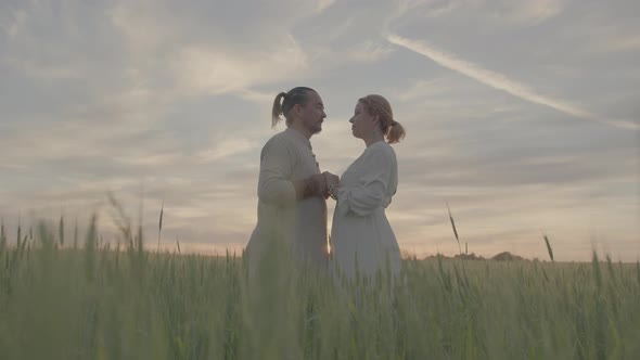 A Heterosexual Slavic Couple Stands in a Wheat Field Looking at Each Other