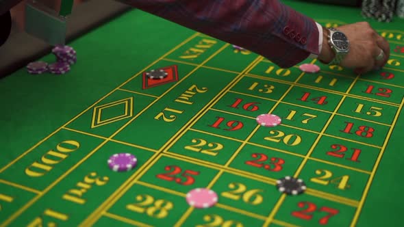 Top View Hands of Men Betting with Chips on a Gaming Roulette Table in a Casino