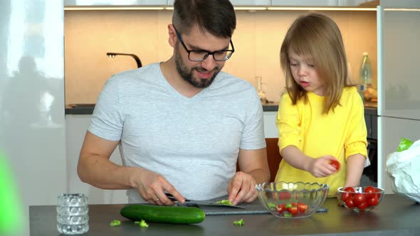 Father and Daughter Prepare Salad of Lettuce Leaves and Tomatoes on Kitchen Background