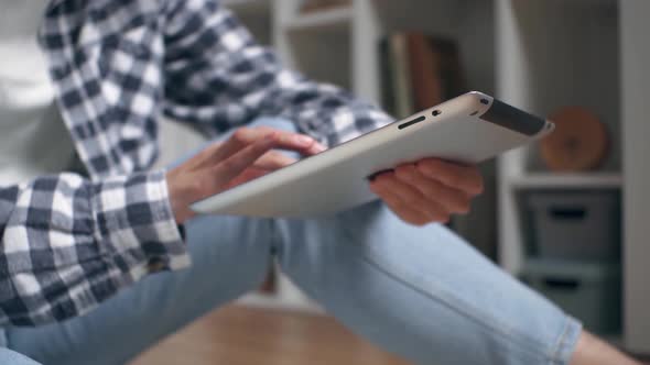 Hands Are Holding A Tablet. The Girl Sits On The Floor And Holds A Tablet Holding It In Her Hands alt