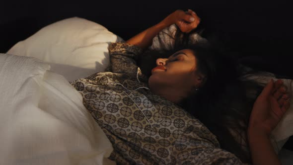 A Woman Wakes Up Early in the Morning at Dawn in Bed From the Rays of the Sun alt