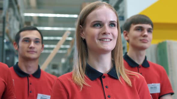 Cute young intern listens to manager during briefing, smiles sweetly, before starting work