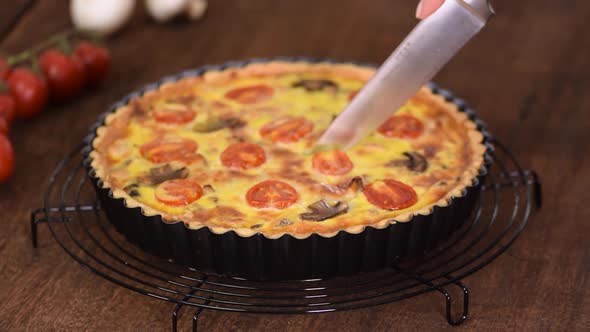 Cutting homemade quiche lorraine with chicken, mushrooms and cheese. French cuisine. alt