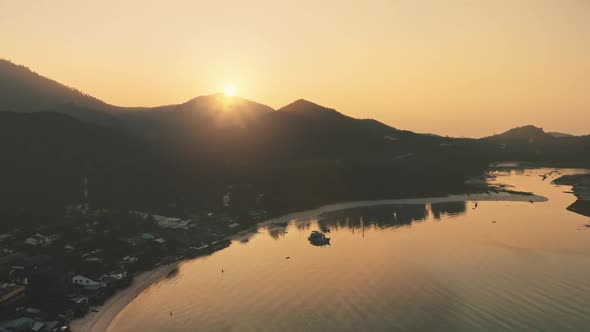 Aerial Orange Sunrise Sky Behind Tropical Island Mountain and Ocean Bay alt
