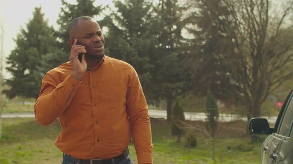 Man Near Scratched Car Calling Insurance Agent alt