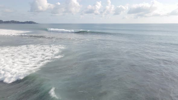 Aerial view of people swimming in Dominical Beach on a surf board, tracking wide shot alt