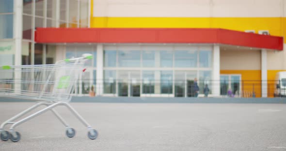 Empty Shopping Cart Rolling at Parking Area Outside Supermarket alt