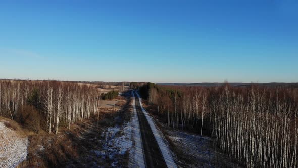 Flying over an asphalt road with markings, Snow-covered roadsides