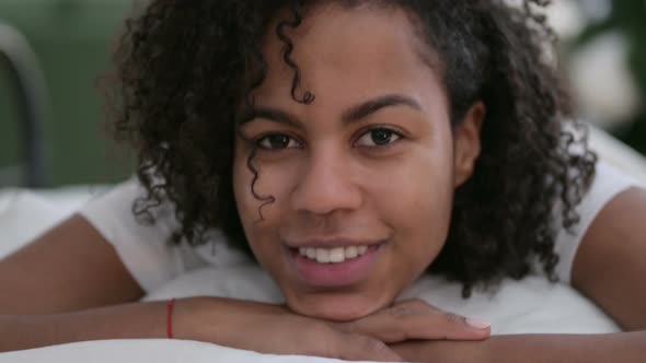 Close Up of Young African Woman Smiling at Camera in Bed alt