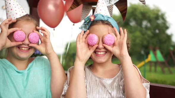 The Birthday Girl and Her Friend Have Fun at a Birthday Party. The Girls Are Holding Pink Cookies alt