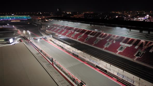 Aerial view of Dubai Autodrome on straight, grand stand, racing during night endurance competition