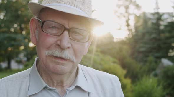 Portrait of Senior Man in Hat Looking Into Camera Nodding Head and Talking alt