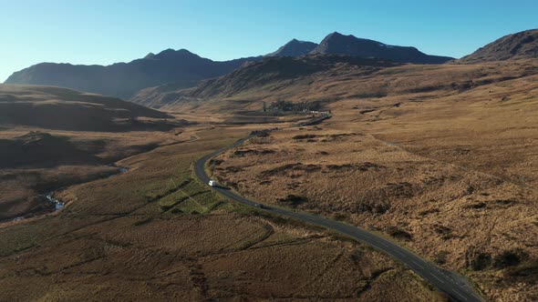 Aerial view of cars on a countryside road through an ample desolate valley in