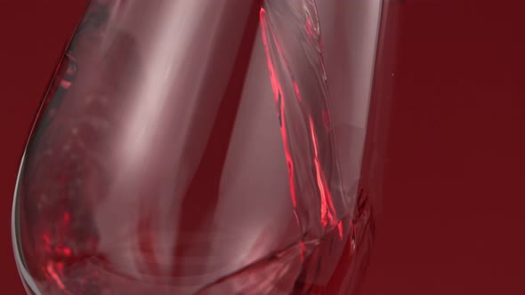 Pouring Red Wine in Super Slow Motion on Red Background alt