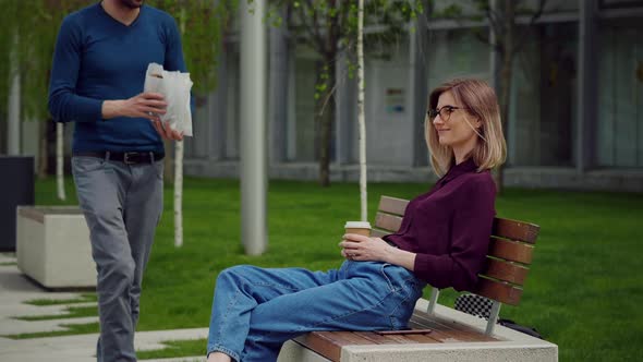 Young happy student colleagues during coffee break patio in the park. alt
