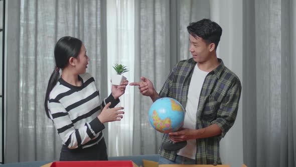 Asian Couple Moving Into A New House Unpacking The Cardboard Boxes And Taking Stuff Out Of Them alt