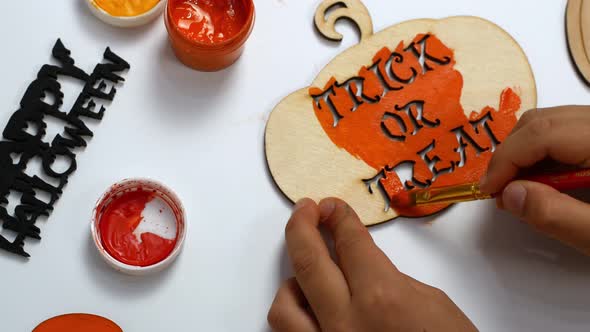 Children make their own Halloween decor. Children paint a pumpkin orange with the inscription alt