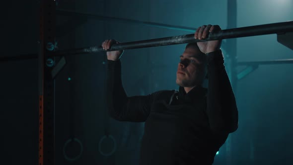 Strong Sporty Man Doing Workout and Pulls Up on Horizontal Bar in Fitness Gym alt