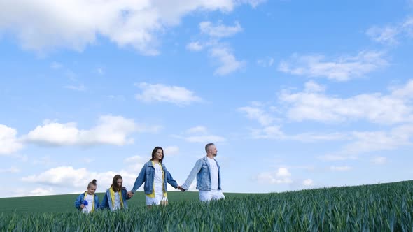 Happy Family of Farmers with Son and Daughter Walking on a Wheat Field alt