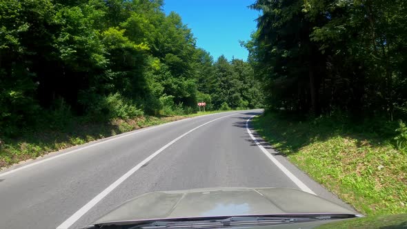 POV shot of driving a car on the road along the forest and mountains. Traveling in the summer by car