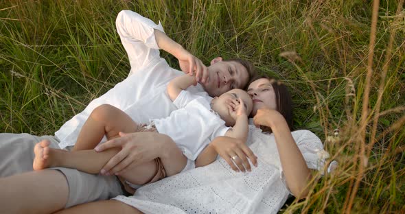 Young Family with Son Relaxing on a Meadow alt
