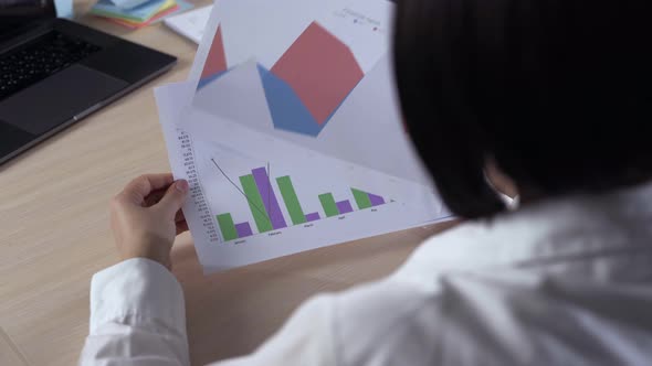 A Businesswoman Analyzing A Colorful Fluctuating Bar Graph On Desk In Office