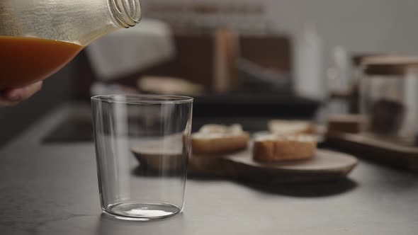 Slow Motion Pour Pumpkin Juice Into Tumbler Glass on Concrete Countertop alt