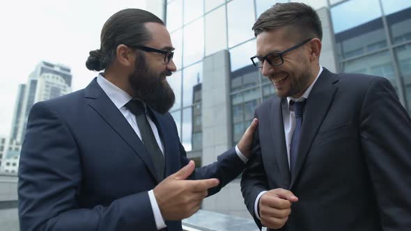 Cheerful Male Colleagues Discussing Successful Meeting With Business Partners