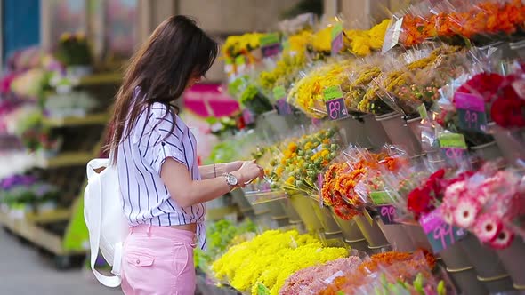 Beautiful Young Woman with Long Hair Selecting Fresh Flowers at European Market alt