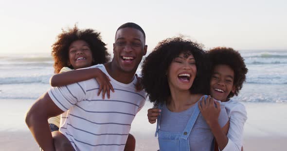Portrait of african american family smiling together at the beach alt