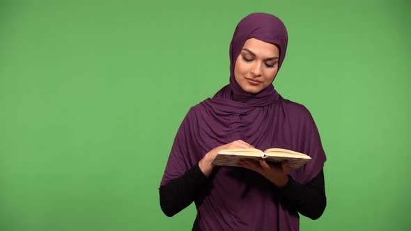 A Young Beautiful Muslim Woman Reads a Book  Green Screen Background